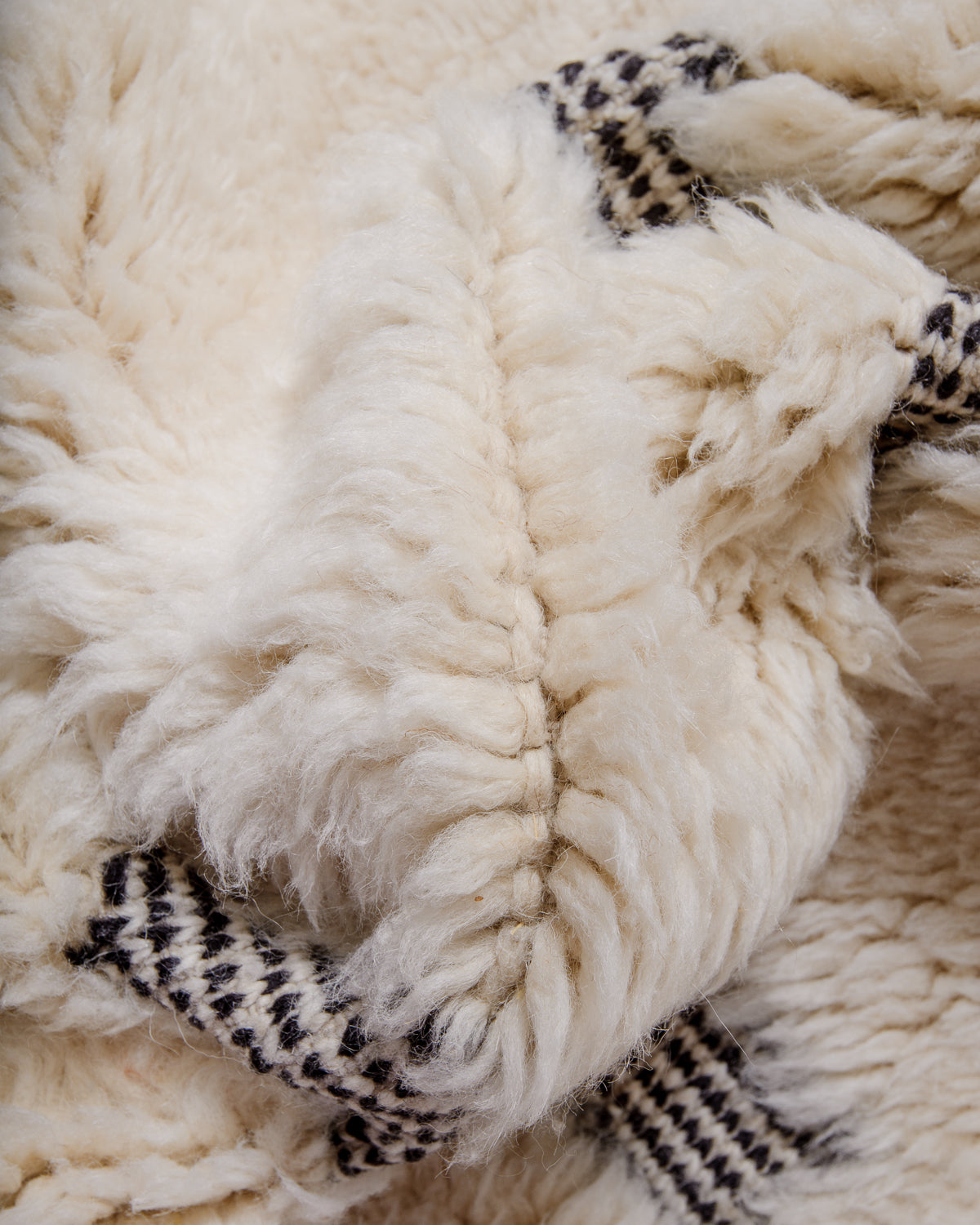 Knotted cream wool on a Beni M'rirt rug with black and white design.